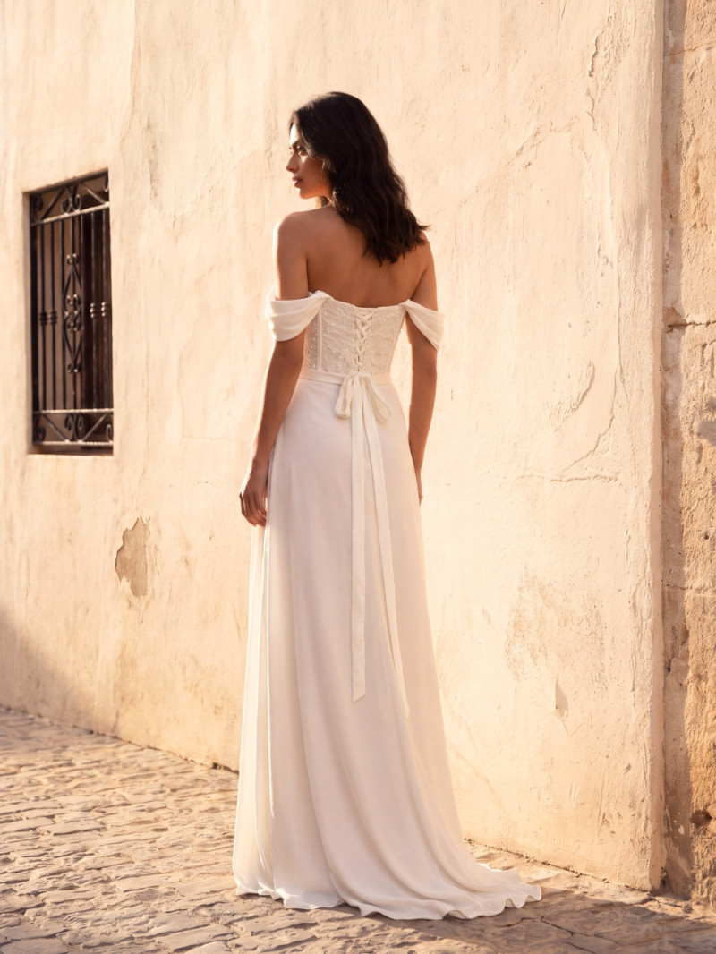 Vista trasera de vestido de novia largo con espalda de cordones, falda fluida y ligera cola